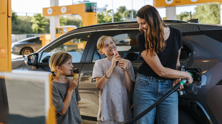 A mother and two daughters pumping gas.