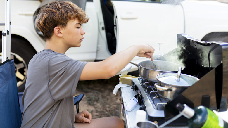 child cooking on camp stove