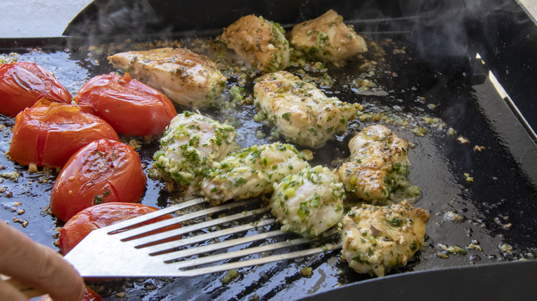Tomatoes and seasoned chicken on a griddle