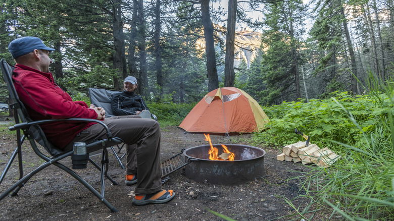 man and woman sitting around a campfire
