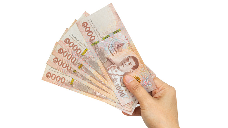 hand holding Thai cash