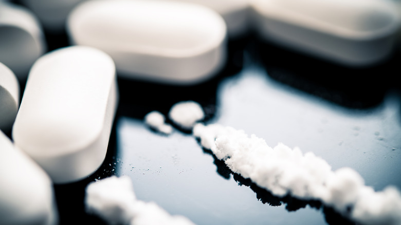 Fentanyl powder lines are seen next to white prescription pills on a reflective surface