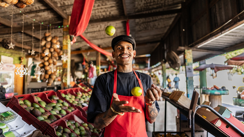 A man in a produce market juggling fruit