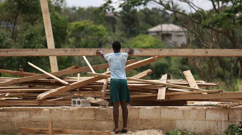 A man rebuilding the structure of a fallen wooden house