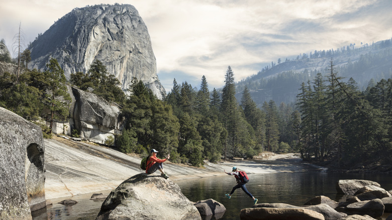 people jumping across boulders in national park
