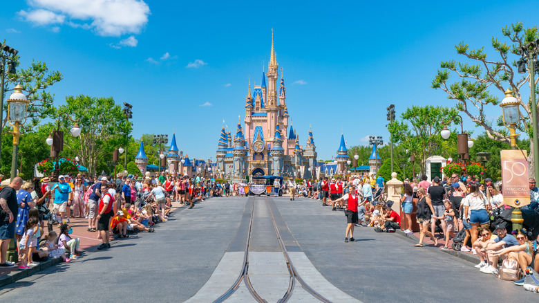 Crowds gathered along the empty parade street with Cinderella's Castle in view.