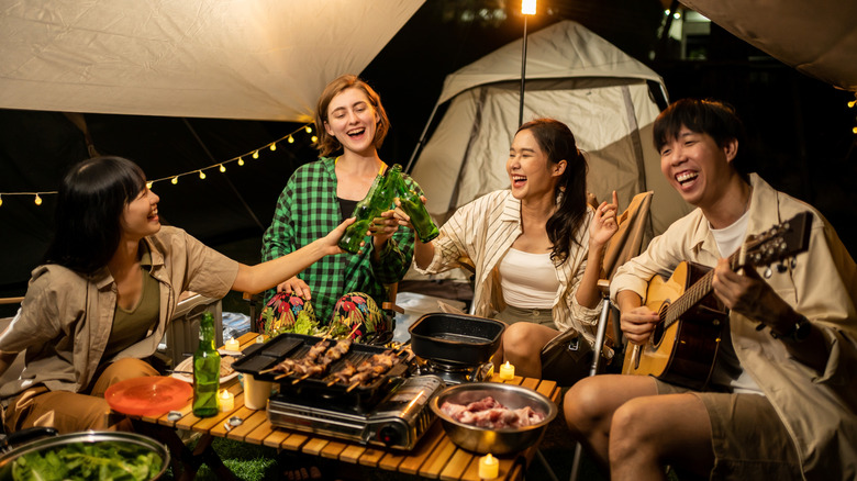 Friends eating dinner at a campsite.