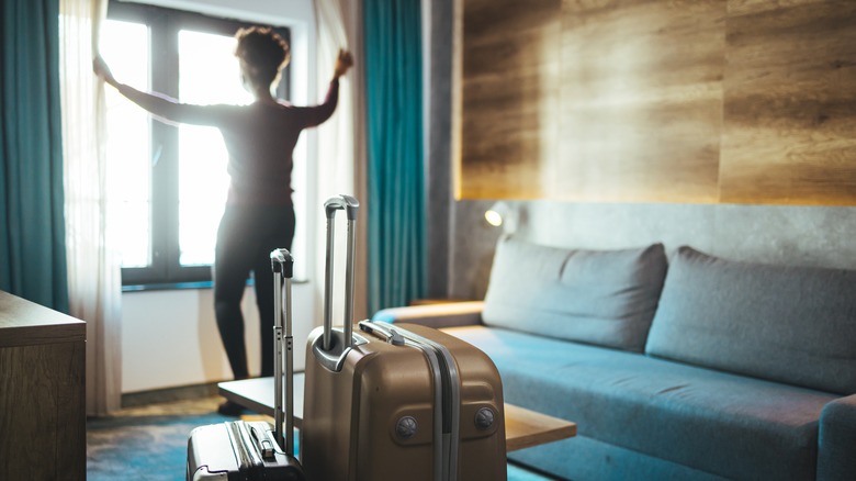 woman opening hotel room curtains