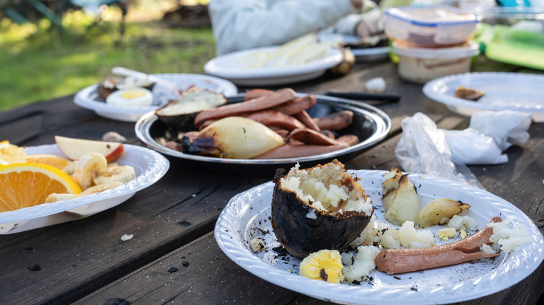 A picnic table filled with leftover food at campsite