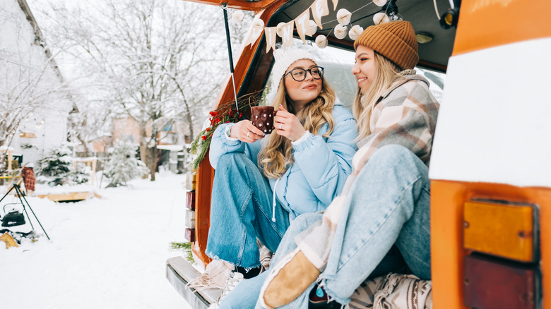 Two cheerful women sitting in a van in winter camp