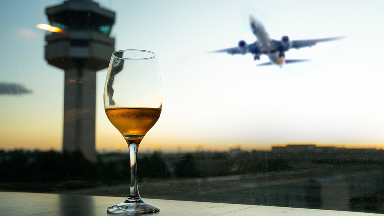 Glass of white wine with an airplane taking off in the background