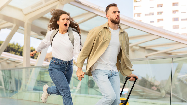 Concerned travel couple running with suitcase