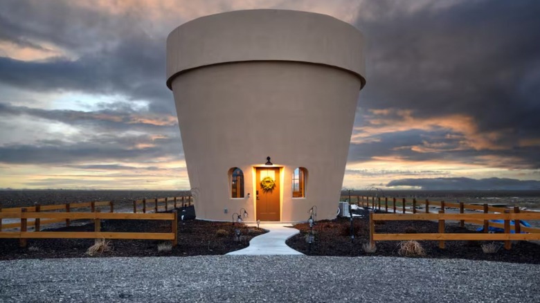 A giant flowerpot airbnb sits against Idaho farmland against a dramatic sky