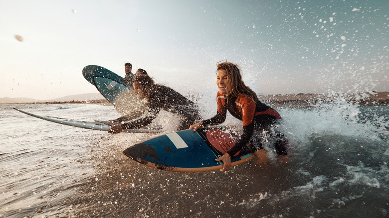 Young carefree woman and her friends having fun while surfing during summer