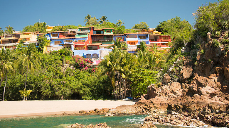Colorful buildings on a hill covered in palms above a beach at Careyes