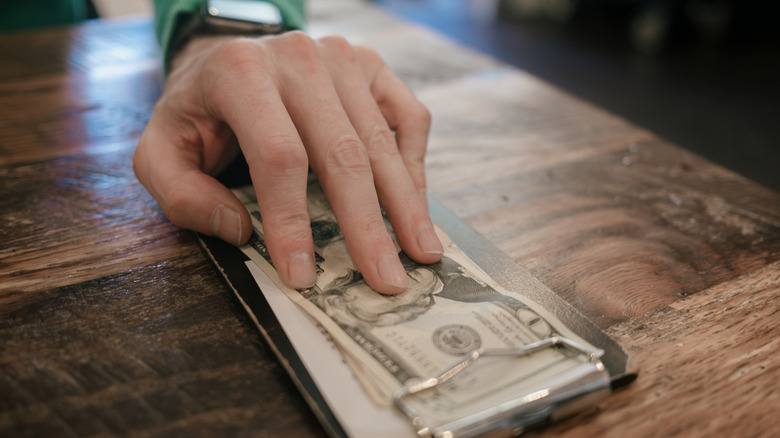 Close up of a man's hand leaving money at a restaurant
