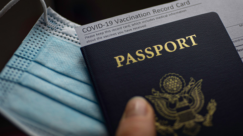 A passport, mask and vaccination record. 