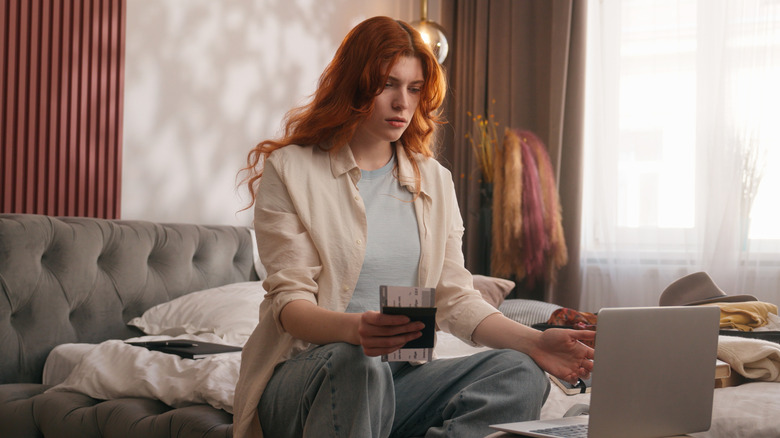 a woman sitting at her laptopp in disbelief because her hotel booking has been cancelled
