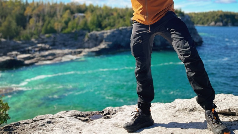 Person in hiking pants on rock overlooking water