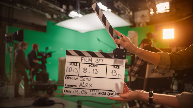 A clapperboard with a film set in the background