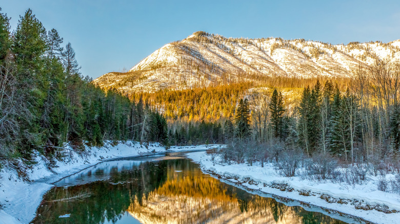 Autumn scene with snow and sunlight on McDonald Creek, Glacier National Park, Montana.