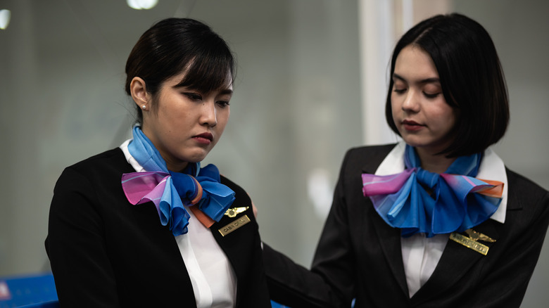 Flight attendant consoling another.