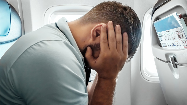 Nervous airplane traveler holding head in hands
