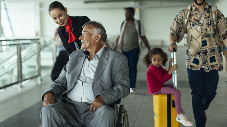 flight attendant helping man in wheelchiar