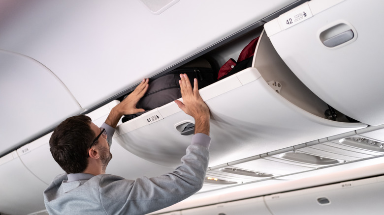 Person storing luggage in overhead bin