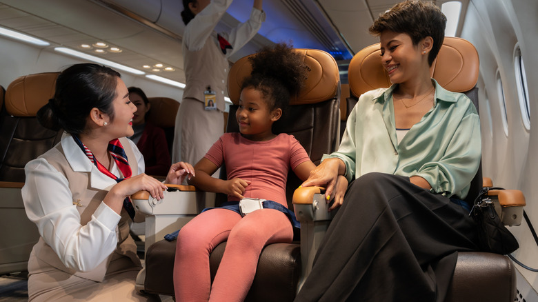 happy flight attendant talking to woman and child