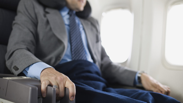 man gripping armrests