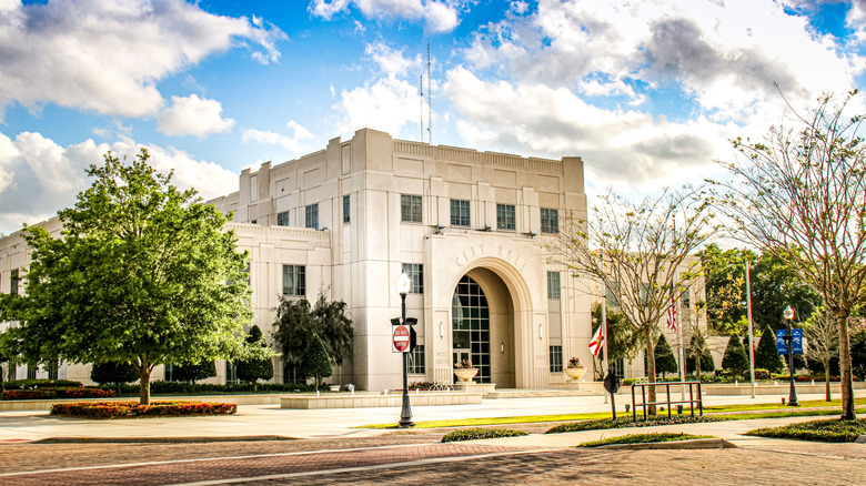 Beige art deco-like building with words City Hall on it on a street, a few trees around it