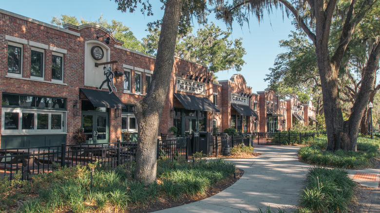 Image of two-story brick buildings and a walking path shaded by large trees.