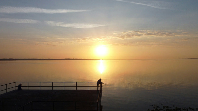 The sun sets behind an angler fishing in Leesburg, Florida