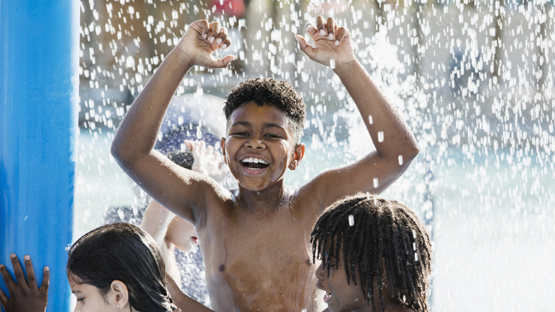 A 10 year old African-American boy having fun playing at a water park