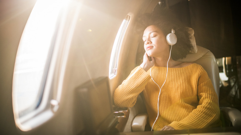 A woman relaxing on a plane with headphones in