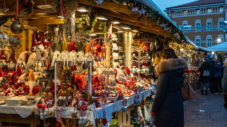 A woman standing in front of an Italian Christmas Market.