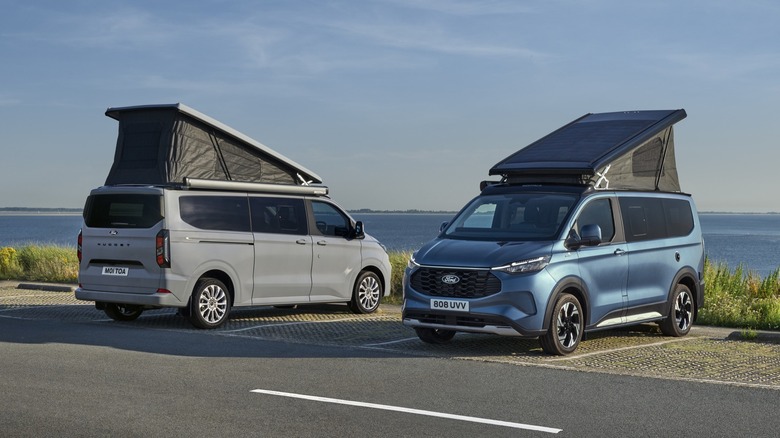 Two Ford camper vans parked with roofs raised.