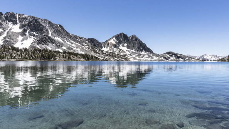 A clear lake in winter with semi snowy mountains around it