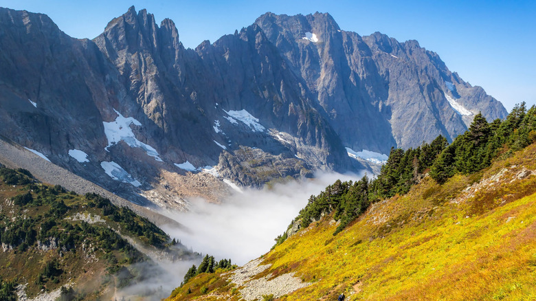 Trail along alpine meadows, backed by dramatic mountain landscape