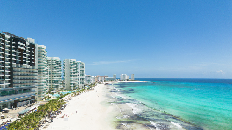 Aerial panoramic view of the beach in Cancun, with white hotels on one side and turquoise sea on the other.