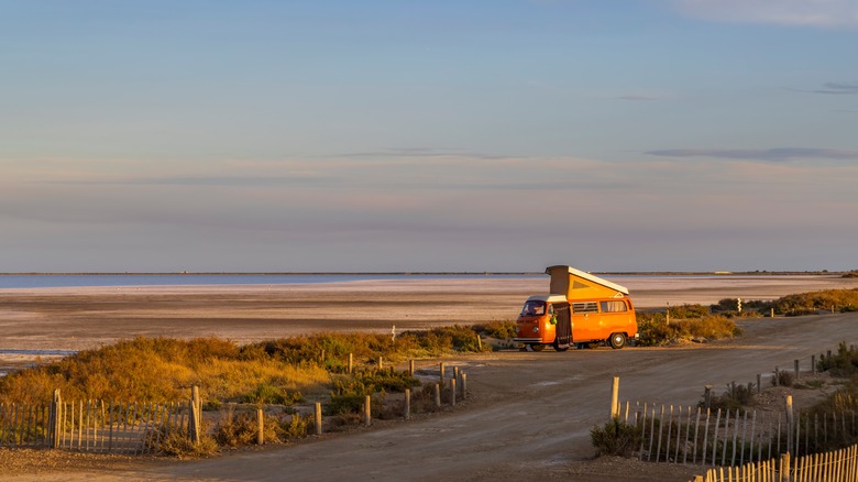 Camping van parked near the beach at sunset
