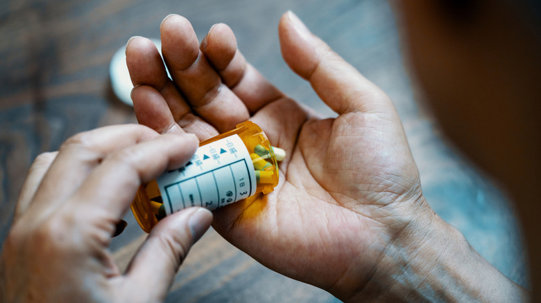 Hand pouring medicine from pill bottle