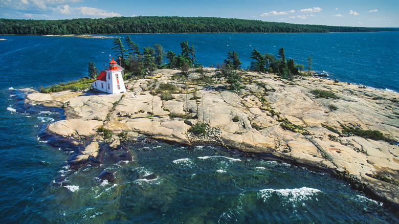A white and red lighthouse on a small rocky island