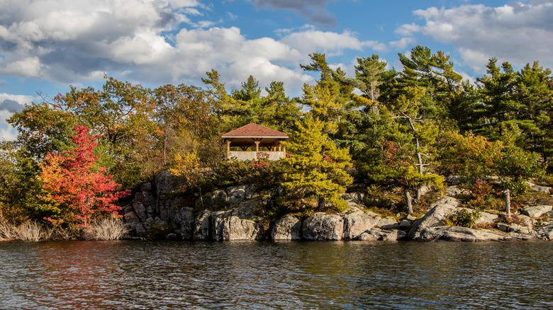 A small wooden structure on a rocky island covered in forest