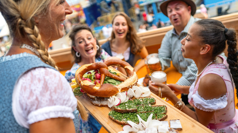 A waitress serving traditional German food on a wooden platter to a group of friends