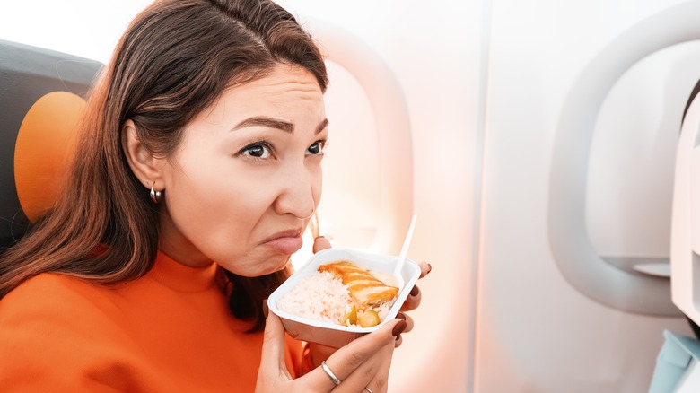 Disgusted woman smelling plane food