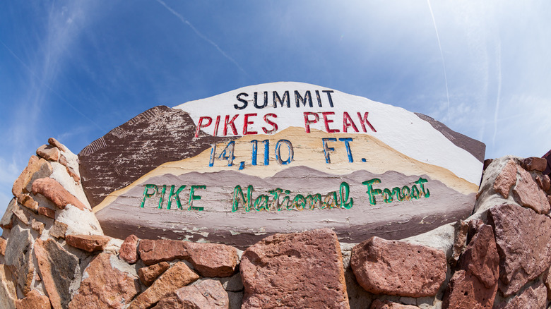 The welcome sign for Pikes Peak Summit on a sunny day