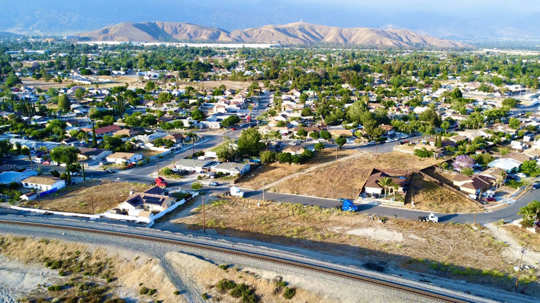 Aerial view of train tracks, buildings, and trees in front of mountains in San Bernardino, California