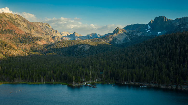 Sunset over mountain ridge and evergreens, with a lake at the bottom